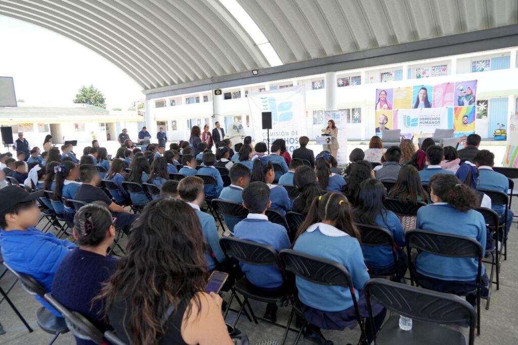 Vista general del público infantil y docente durante la presentación del libro “Meztli” en una escuela primaria, con atención puesta en la autora y autoridades presentes.